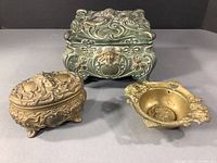 Art Nouveau decorative boxes and brass dish arranged together showing overall size, shape and style.