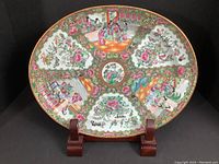 Frontal view of the entire oval platter on wooden stand showing overall Rose Medallion design