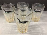 Four antique seeded glass tavern glasses with hand-painted whale and rim band motifs displayed together.