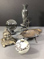 Group photo showing all five items including crystal ball on stand, Native American head ink well, silver plate bowl, white vase with sterling overlay, and Victorian Meriden bud vase.
