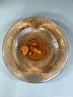 Top-down view of circular hammered amber glass bowl on flat surface