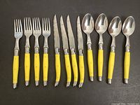 Full set laid out, showing 4 forks, 4 knives, 4 spoons with yellow handles and honeybee design.