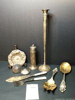 Full overview of all nine silver tableware items on black background