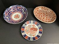 Three porcelain pieces arranged: large scalloped bowl left, oval platter right, small scalloped platter front