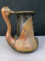 Side view of brass swan vase showing detailed swan head and wing design, highlighting patina and craftsmanship