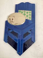 Front view of the ceramic wall plaque showing the entire piece with a blue chair and beige cat.