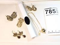 Six pairs of earrings and one necklace arranged around ring display