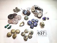 Overview of entire collection laid out on white fabric, showing various styles, colors, and sizes of buttons and the cufflink set.