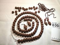 Coiled long carved wood bead strand, loose beads, broken seed/glass bead strand, and two larger carved figure pendants