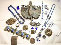 Photo showing all jewelry pieces and brass trinket tray including blue bead necklaces, brooches, bracelets, and pendants.
