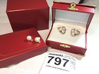 Two red presentation boxes with pair of earrings displayed