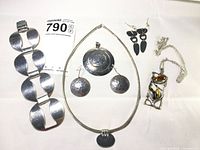 All jewelry pieces displayed on white background showing bracelet, necklaces with pendants, and pairs of earrings