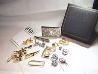 Collection laid out on white background showing multiple cufflinks, tie clips, tie tacks, money clips, ring and box
