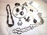 Photo showing all 14 pieces of the collection spread out on a light background including necklaces, earrings, rings, pendants, and brooches.