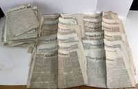 Stack of over two dozen folded New-York Tribune newspapers laid out on table