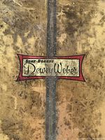 Close-up of Dewey Weber logo on Coco Bolo stringer surfboard, showing wear and age.