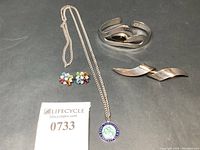 Full lot view showing all four pieces: swirl brooch, medallion necklace, cuff bracelet, and stud earrings.