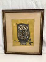 Framed artwork showing entire piece with owl print on yellow background, wooden frame.