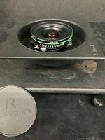 Lens mounted in rectangular black board with cap beside it