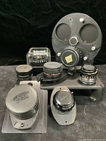 Overall view of six enlarger lenses mounted on various board plates against black background