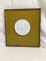 Full view of framed Royal Copenhagen bisque porcelain plaque mounted on mustard velvet background.