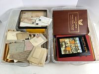 Two clear plastic storage boxes filled with envelopes, letters, and stamp albums