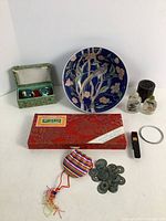 Full view of all nine vintage Asian items including painted bowl, snuff bottles, incense burner, pearl powder case, coin purse with coins, ink stamper, bracelet, and Baoding balls set