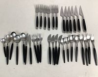 Overview photo showing all 34 flatware pieces arranged by type on white surface. Includes forks, knives, spoons all with black handles and metal tips.