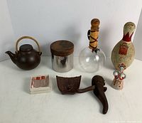 Lot of vintage and collectible items shown together, including Brunswick King pin, Erhard canister, porcelain figurine, nutcracker, okimono mouse, Arabia teapot, Pyrex decanter, and mini shakers.