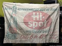 Full view of faded cloth banner with large bottle graphic, Hi-Spot logo, and advertising text.