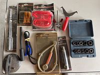 Photo showing assorted automotive tools including tension testers, socket set, wire caps, and various hand tools.