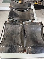 Four car moving dollies stacked and showing their curved platforms and steel frames.