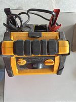 Top view of CAT portable booster pack showing battery clamps and handle for portability.