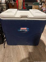 Front view of the blue and white Coleman Xtreme5 cooler showing the logo and cup holders on lid.