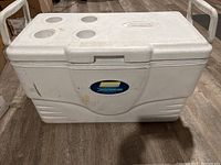Front view of white Coleman Xtreme Marine cooler, showing logo and body with some dirt marks and scuffs.