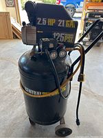 Front and side view of the black Central Pneumatic 2.5 HP air compressor showing 21 gallon tank and two pressure gauges, power cord, handle, and wheels.