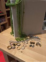 Photo showing entire lot care. Beaded necklace draped over white box, other jewelry spread on wooden table.