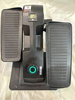 Top view showing two large treaded pedals and digital display with buttons on the elliptical machine.