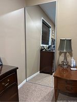 Front view of the full length mirror showing reflective glass with a slim silver frame hanging on the wall.