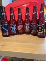 Six Labatt Blue NHL Original 6 bottles and one Labatt 50 Ale stubby bottle arranged in a row on a table, showing team logos and Stanley Cup Championship years.