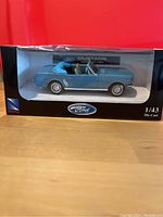 Blue 1964 Ford Mustang Convertible die cast model in original packaging showing side profile on display stand inside box