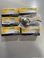 Six boxed Legend Dummy Leverset closet door handles in satin nickel finish, with one handle unpacked and visible on bubble wrap.
