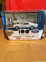 Front view of Matchbox Ford 100 Years Collection 1967 Mustang die cast model in clear display packaging showing the white car and blue stripes with collector logos.
