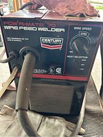 Front panel of Century Powr-Mate 70 wire feed MIG welder showing model name, wire speed and heat selector dials