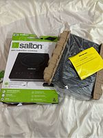 Salton induction cooktop with its packaging and instruction manual visible on white background.