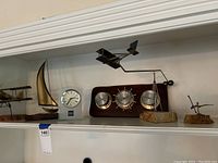 Shelf with airplane model, sailboat, and barometer decor pieces
