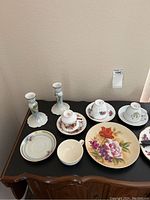 Multiple white ceramic candle holders with floral details, various floral patterned china tea cups and saucers, small decorative plate