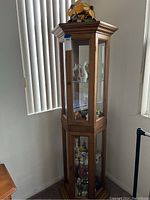 Full view of hexagonal curio cabinet showing its height, shape, and position by window