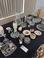 Overview of assorted glassware, porcelain, and china placed on black tablecloth.