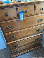 Front angled view of the highboy dresser showing five drawers and original decorative metal hardware attached. Small tag with number 202 visible on upper drawer.